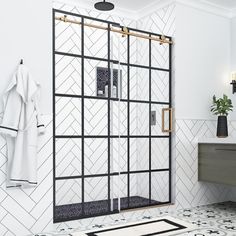 a white bathroom with black and gold accents on the shower door, sink and mirror