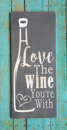 a sign that says love the wine you're with on a blue wooden background