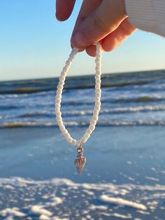 A white seed bracelet with a beautiful shiny seashell charm in the middle. Really cute and matches every outfit, perfect for kids and adults. Comes w/ 1 free sticker! Adjustable White Stretch Bracelet With Beachy Style, White Adjustable Stretch Bracelet With Beachy Style, White Stretch Bracelet With Pearl Charm And Round Beads, White Stretch Bracelet With Pearl Charm, Adjustable White Pearl Bracelet For Beach, Handmade White Pearl Bracelet For The Beach, Ocean-inspired White Bracelet As Gift, White Ocean-inspired Jewelry With Round Beads, Ocean-inspired White Bracelet Gift