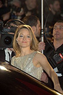 a woman in a silver dress holding an umbrella next to a man with a camera