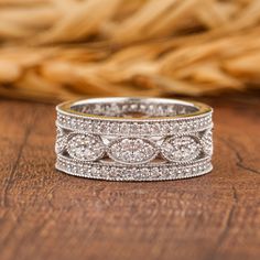 a wedding band with three rows of diamonds on top of a wooden table next to a basket