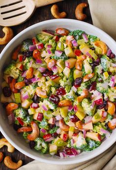 a white bowl filled with broccoli, fruit and nuts