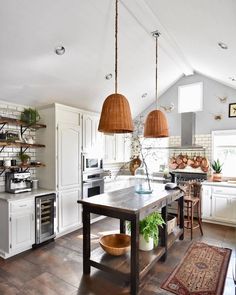 a kitchen with two pendant lights hanging from the ceiling and an island in the middle