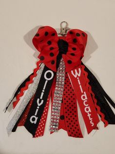 a red, black and white bow with polka dots is hanging from a key chain