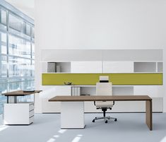 an office with white, green and black furniture in the middle of a large windowed area