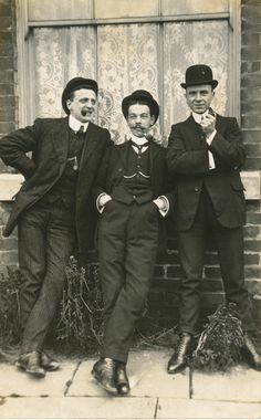 three men standing next to each other in front of a building with their hands on their hipss