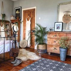 a bedroom with a bed, dresser and plants in pots on the floor next to it