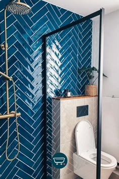 a blue tiled bathroom with a toilet and shower