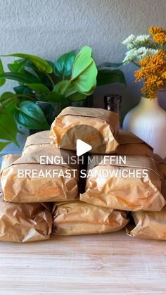 a pile of bread sitting on top of a wooden table next to a vase with flowers