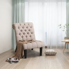 a living room with a chair, ottoman and coffee table in front of a curtained window