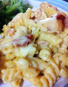 a plate with pasta, broccoli and bacon on it next to a fork