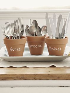 four pots with forks and spoons in them sitting on a plate next to silverware