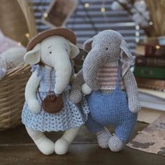 two knitted stuffed animals sitting next to each other in front of a basket filled with books