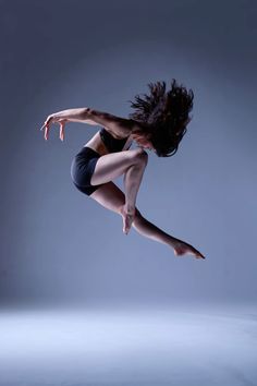 a woman is jumping in the air with her legs spread out and one leg bent