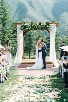 a bride and groom kissing under an outdoor wedding ceremony