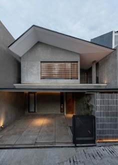 a modern house with an open garage and large windows on the roof, in front of a gated yard