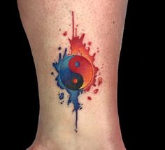 a colorful tattoo on the ankle with watercolor splatters and a yin symbol