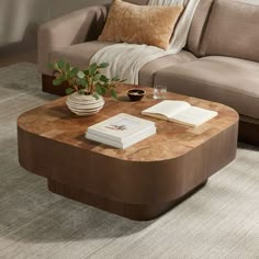 a living room with a couch, coffee table and books on the end tables in front of it