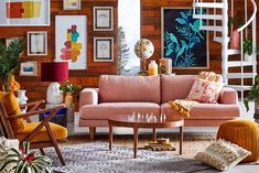 a living room filled with lots of furniture and pictures on the wall next to a spiral staircase