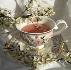 a tea cup and saucer sitting on top of a plate with flowers in it