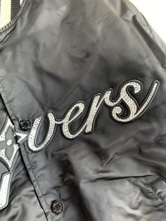 Embrace sporty sophistication with the Louis Vuitton-inspired Embroidered Nylon Baseball Blouson. This statement jacket reimagines classic varsity styling with a luxurious touch. The sleek black nylon is adorned with eye-catching embroidered patches, showcasing "LV Lovers" lettering and playful motifs. The contrasting ribbed collar, cuffs, and hem offer a snug fit and a touch of sporty flair. This versatile blouson is perfect for layering and adds a touch of high-fashion to any casual ensemble. Blouson Jacket, Statement Jacket, Loafer Sneakers, Bottega Veneta Shoulder Bag, Black Nylon, Black Nylons, Embroidered Patches, Loafer Shoes, Snug Fit