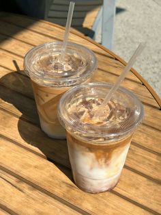 two iced coffees sitting on top of a wooden table next to eachother