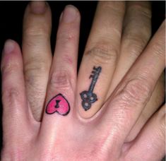 two fingers with tattoos on them and one has a key to the heart shaped hole