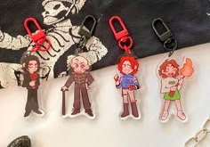 four keychains with cartoon characters on them sitting next to a pair of scissors