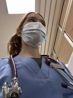 a woman in scrubs with a stethoscope on her shoulder and wearing a face mask