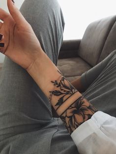 a woman's arm with a flower tattoo on her left wrist and the other hand