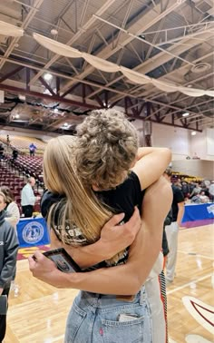 two people hugging each other on a basketball court