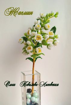 a vase filled with balls and flowers on top of a table