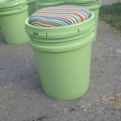 three green trash cans with colorful striped seats on them