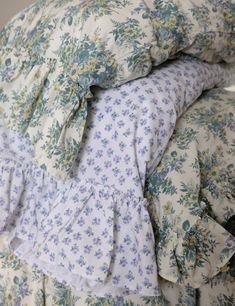 pillows stacked on top of each other with ruffles and floral print in them