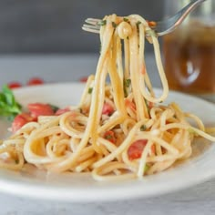 a fork full of spaghetti with tomatoes and parmesan cheese on the side, ready to be eaten