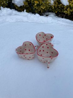 three heart shaped bowls sitting in the snow