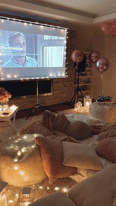 a living room filled with lots of pillows and lights on the wall next to a flat screen tv