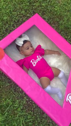 a baby doll in a pink frame on the grass