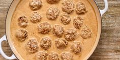 a casserole dish filled with meatballs and gravy on a wooden table