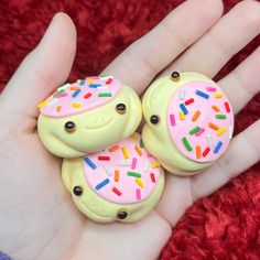 two handmade donuts with sprinkles on them sitting in someone's palm