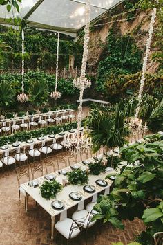 tables and chairs are set up in the middle of an outdoor garden area with greenery