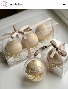 four cupcakes in clear boxes with bows on them