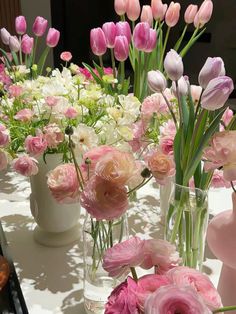 a table topped with vases filled with pink and white flowers next to each other