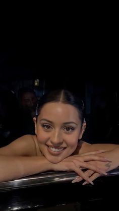 a smiling woman leaning on the edge of a car