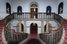 an ornate staircase with red carpet and white walls