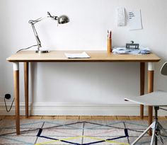 a desk with a chair and lamp on it in front of a white walled wall