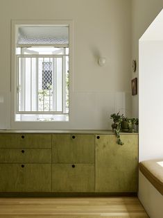 an empty kitchen with wooden floors and white walls, has a window above the counter