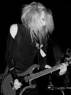 a woman with blonde hair playing a guitar