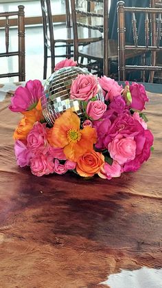 a vase filled with pink and orange flowers on top of a wooden dining room table