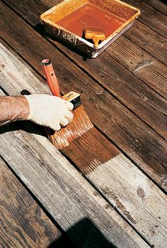 a person in white gloves is painting a wooden table with brown paint and a brush